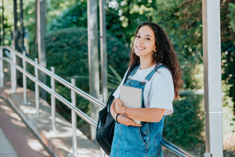 Female african student standing outdoors university holding books. Portrait of young african woman looking at camera, Education concept